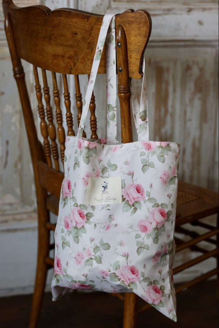 Floral tote bag hanging on a wooden chair against a rustic wall.